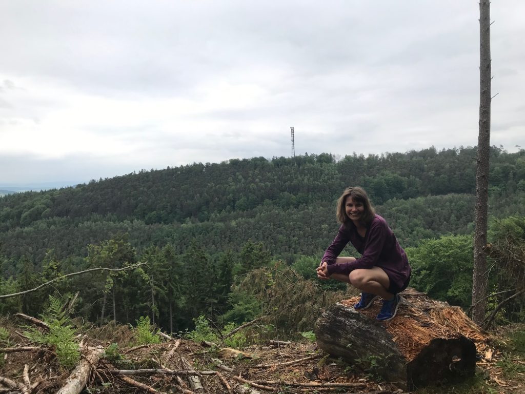 Frau Seidel auf einem liegenden Baumstamm im Wald